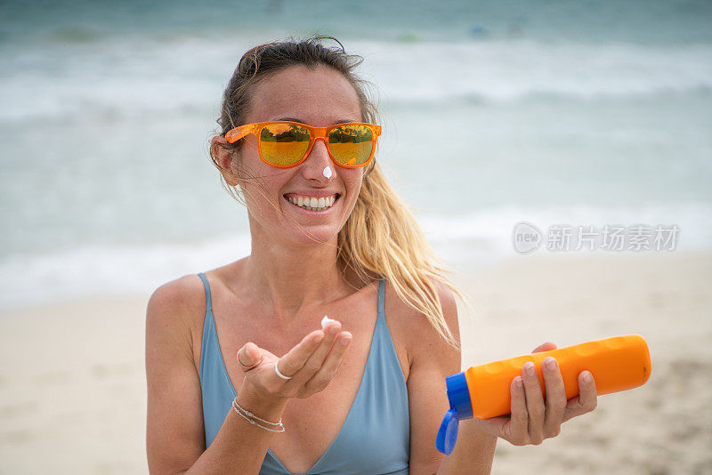 夏日――年轻女子在海滩上涂抹防晒霜，保护皮肤