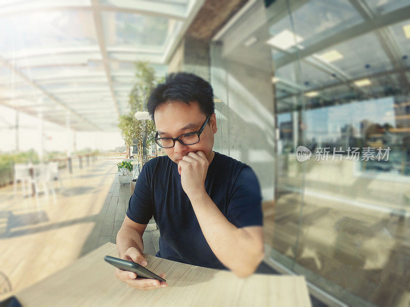 一名日本男子在咖啡店玩手机。