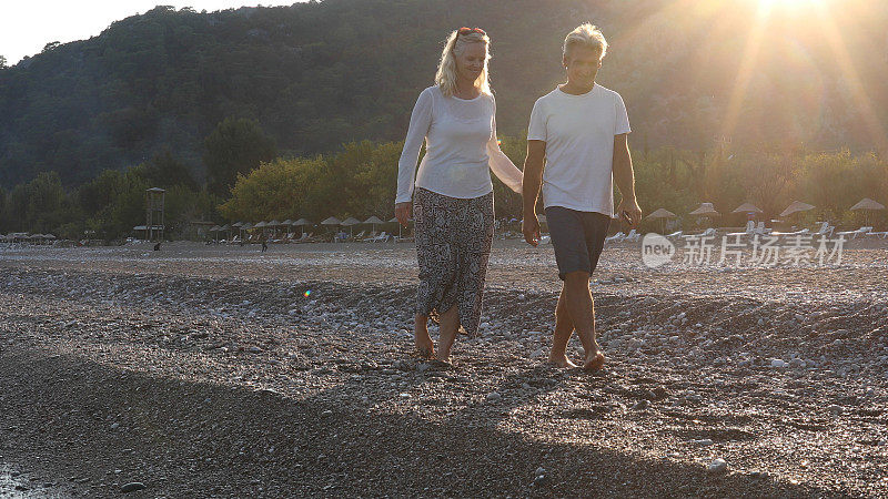 日出时，一对成熟的夫妇在海滩上散步