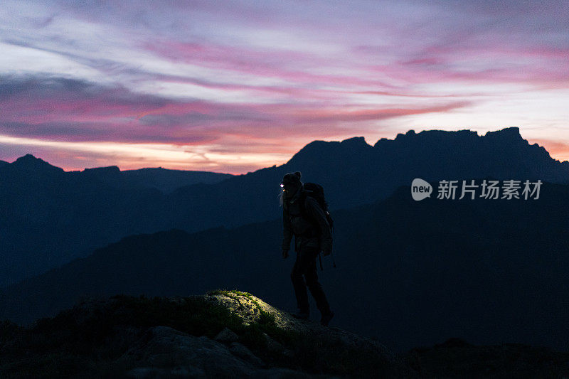 日出时，女徒步旅行者穿过山脊