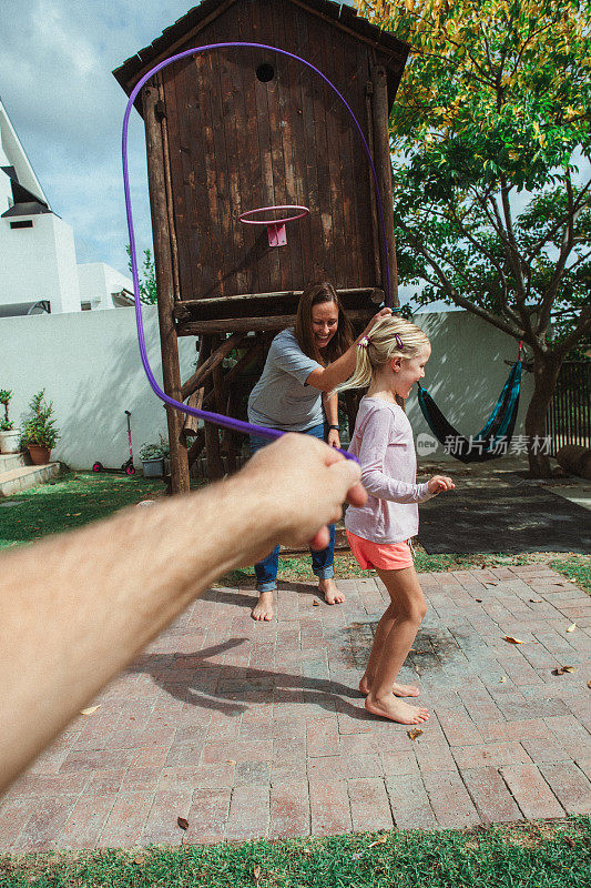 跳绳和可爱的金发蹒跚学步的女孩在后院玩