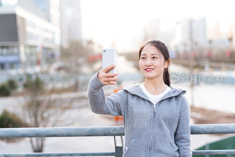 亚洲年轻女子在城市公共广场使用手机