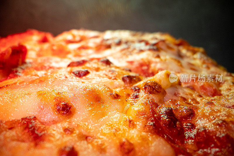 超近距离广角微距拍摄油腻融化的奶酪在美味热气腾腾的深盘辣香肠披萨上新鲜出炉的烤箱在一个冷却架下加热灯