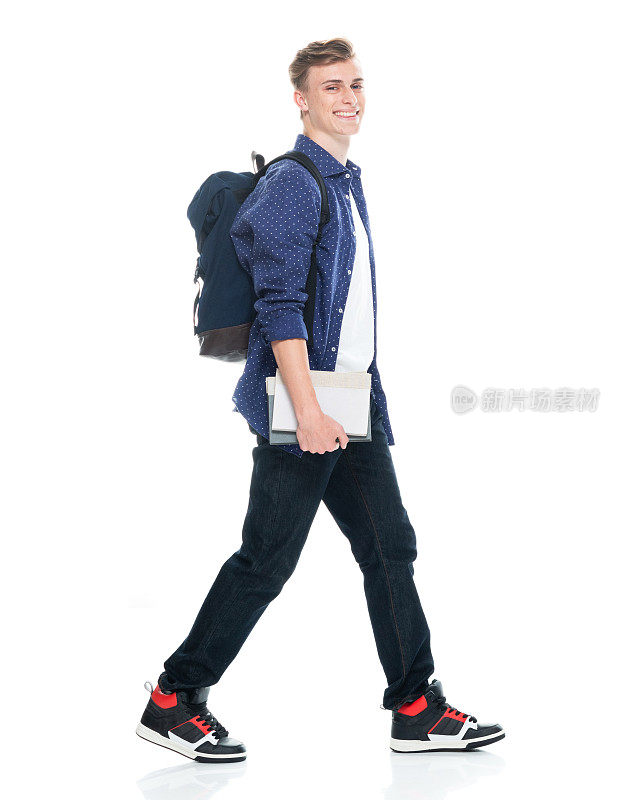 高中男生背着书包拿着书走在前面，背景是白色