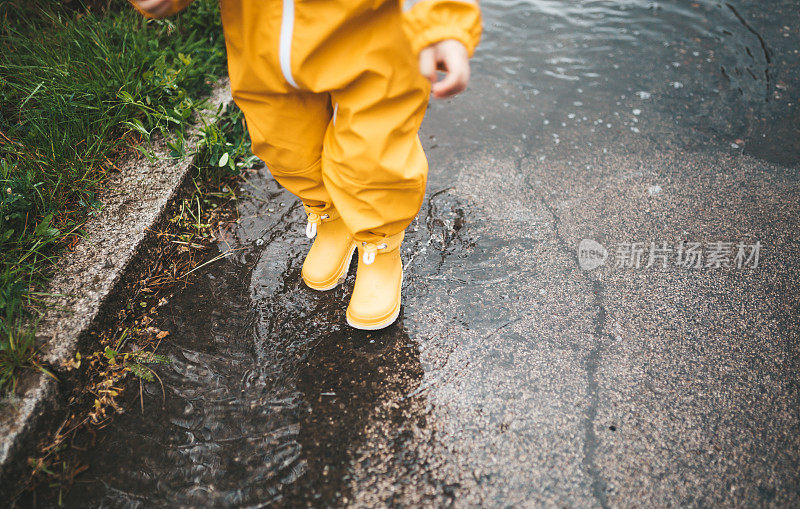 小男孩在雨中玩耍，跳进水里画画