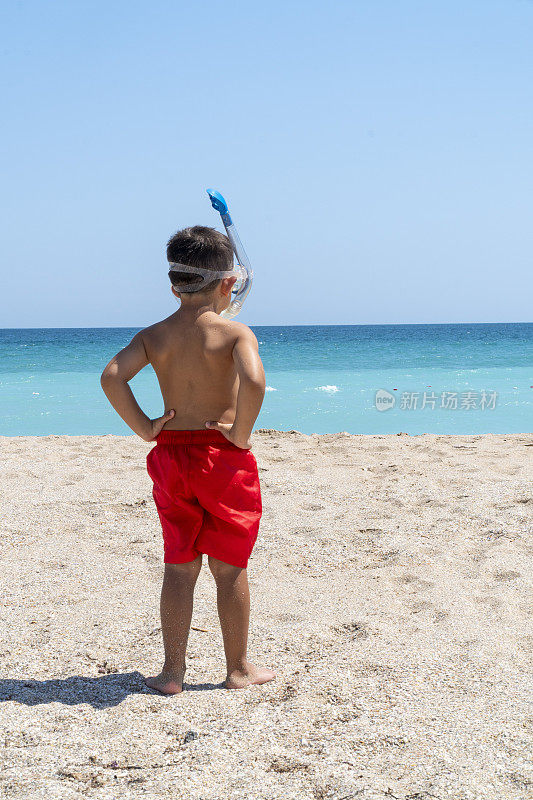 戴着通气管的小男孩准备在空旷的海滩上游泳