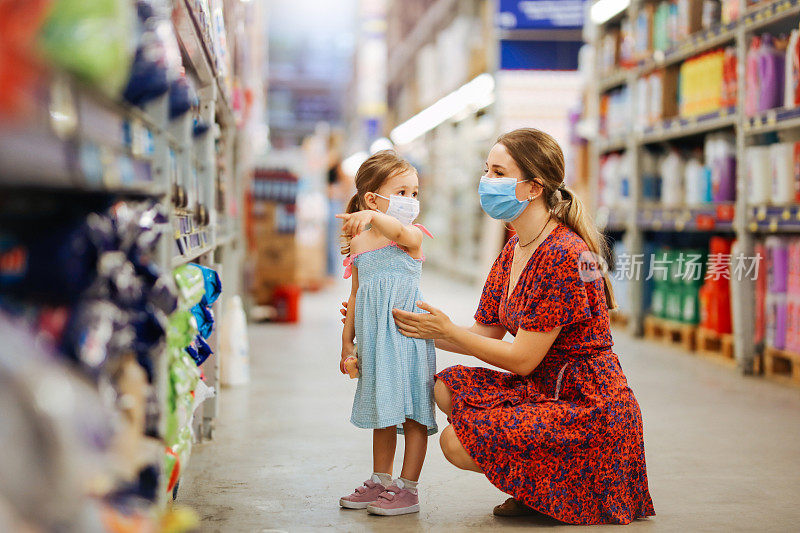 带着女儿戴着防护面具购物的女人