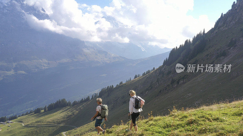 鸟瞰图的徒步旅行夫妇穿越高山草地，在日出