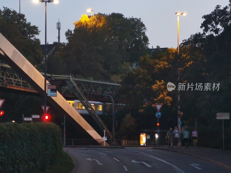 在一个温暖的夏夜，伍珀塔尔浮动铁路穿过一条城市道路