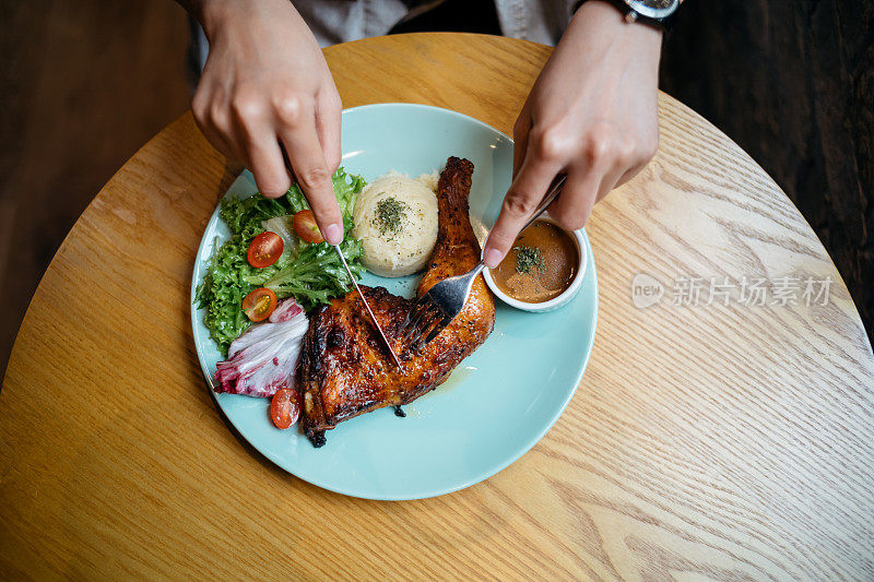 一位亚洲妇女正在餐馆享用烤鸡大餐