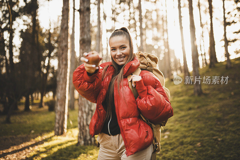 女徒步旅行者吃苹果，在日出时休息