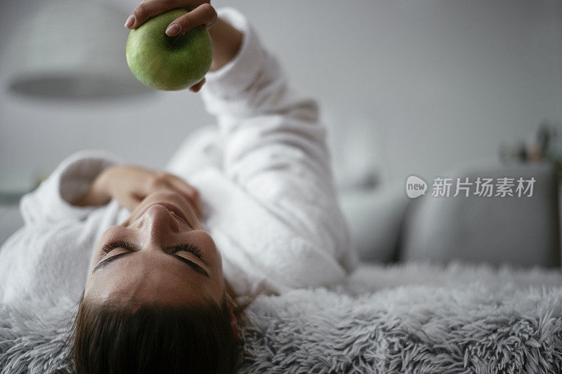 穿着浴袍吃苹果的漂亮女人。