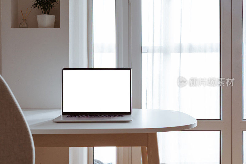 笔记本电脑与空白白色屏幕在办公室办公桌内部。时尚的工作模型。