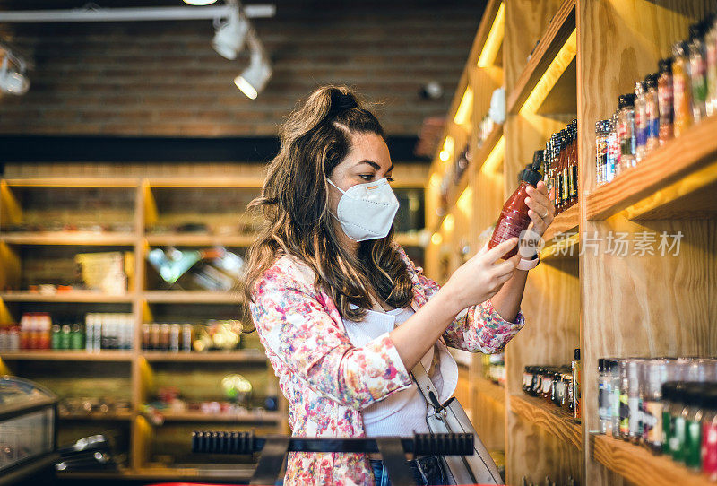 在超市选购罐装食品的妇女。戴防毒面具