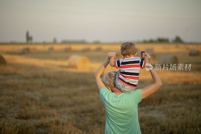 夏日里，年轻的母亲在大自然中背着年幼的儿子