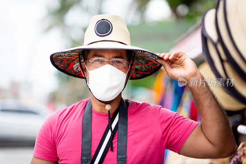 度假期间，一名戴着面罩和帽子的男子在市场里看着摄像机