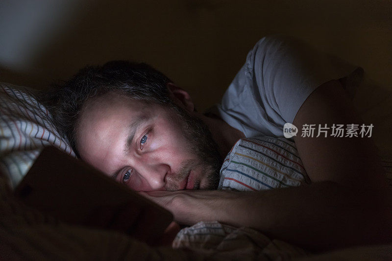 成年困倦的男性深夜醒来在床上上网、聊天、调情