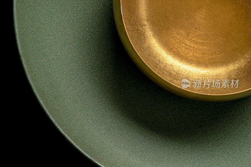 风化的金色金属碗在绿色陶瓷板