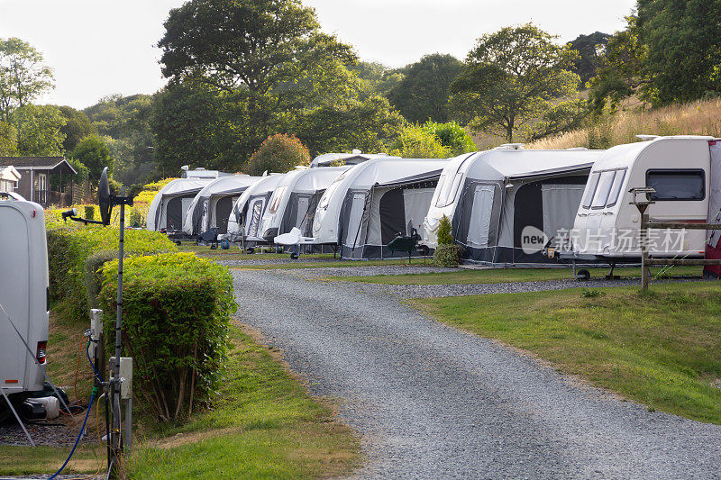 大篷车在北威尔士的大篷车地点排成一排，因为人们在夏天的几个月里在美丽的乡村享受休息。