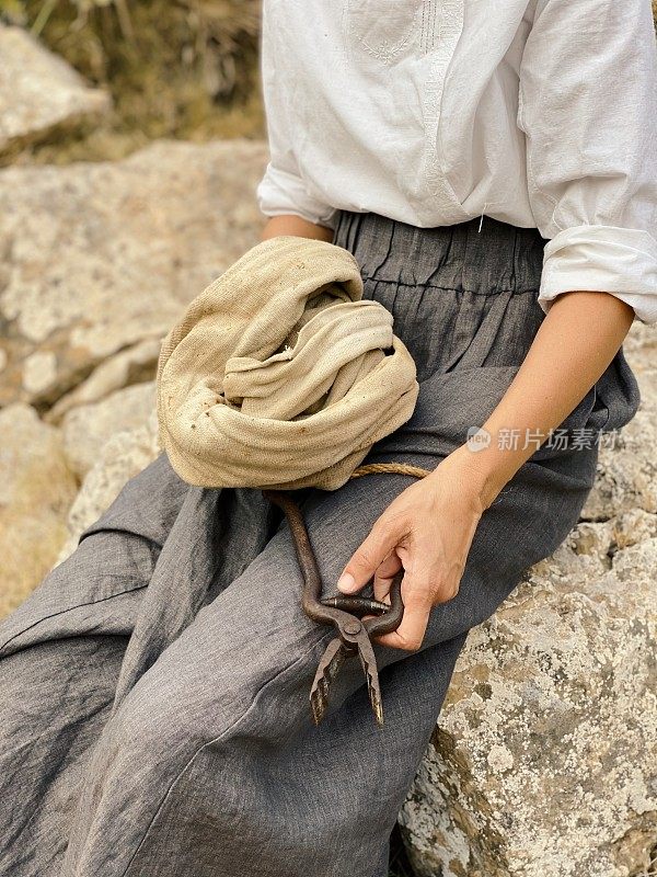 一个女人倚在石头上，手里拿着一把古董剪子
农村