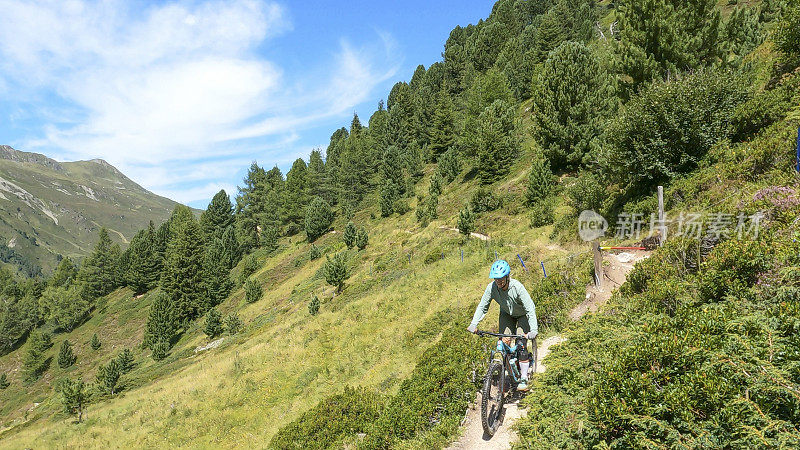 女人沿着阳光明媚的自行车道骑山地车