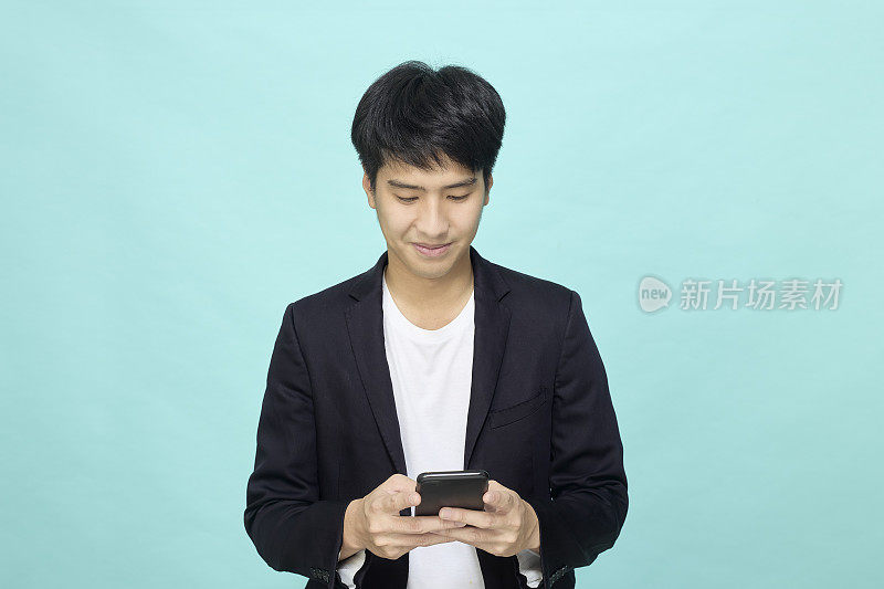 英俊的年轻亚洲商人发短信工作，持有智能手机