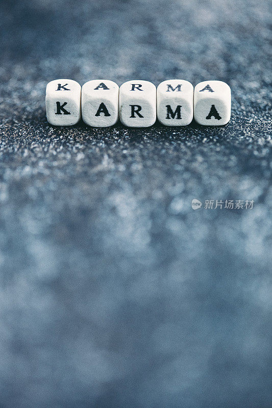 字母表在深灰色的桌子上阻止拼写单词KARMA。使用复制空间拍摄