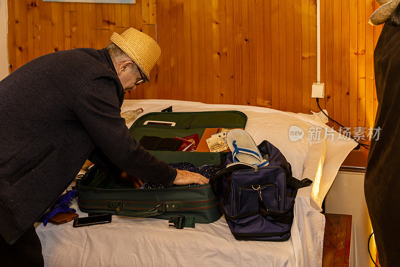 一位年长的男士把东西装进包里，准备去度假旅行
