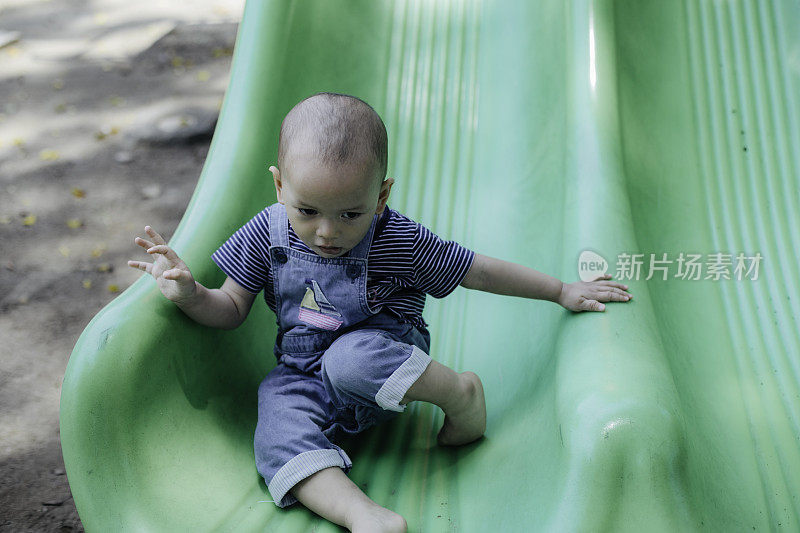 一个小男孩在操场上玩滑梯