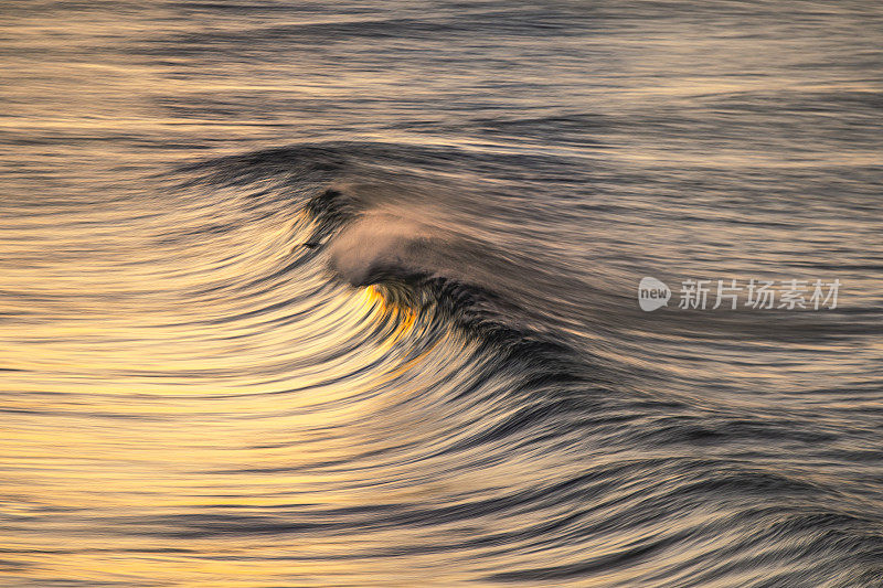 金色的海浪在沙滩上反射出明亮的金色日出