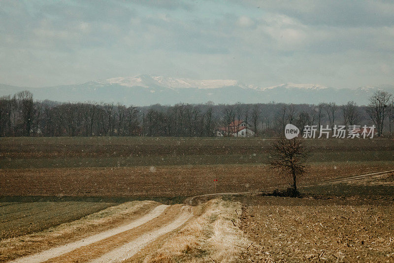 多云天空下的农田。下雪。