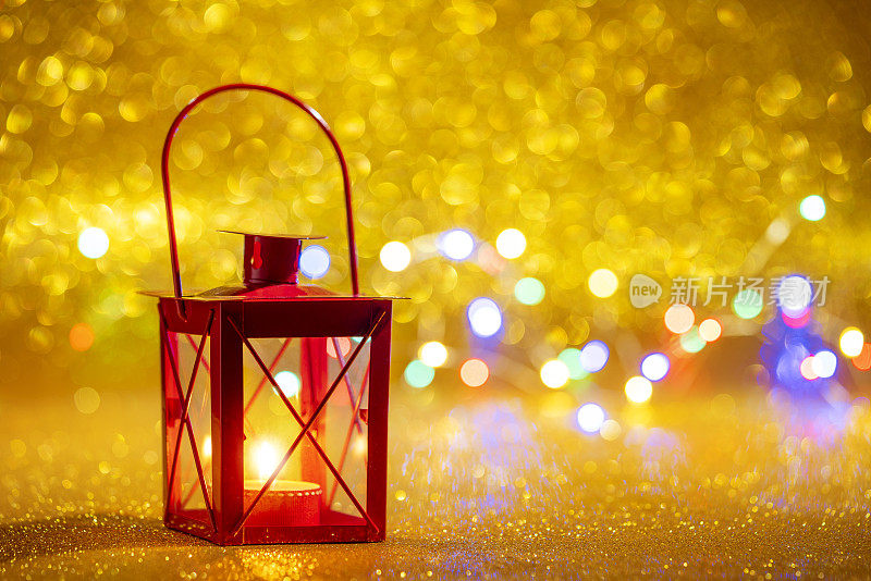 红色的蜡烛灯笼在金色闪闪的圣诞背景与模糊的圣诞灯