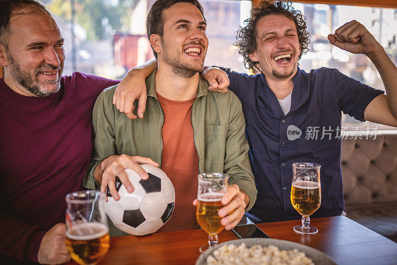 兴奋的体育迷们一边在酒吧里观看比赛，一边为自己的球队加油