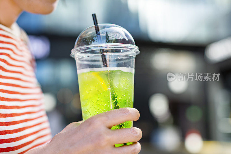 用塑料杯盛着柠檬水的女人的手