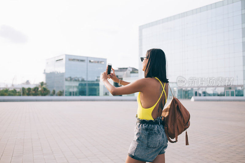 旅行女子在街上用手机拍照