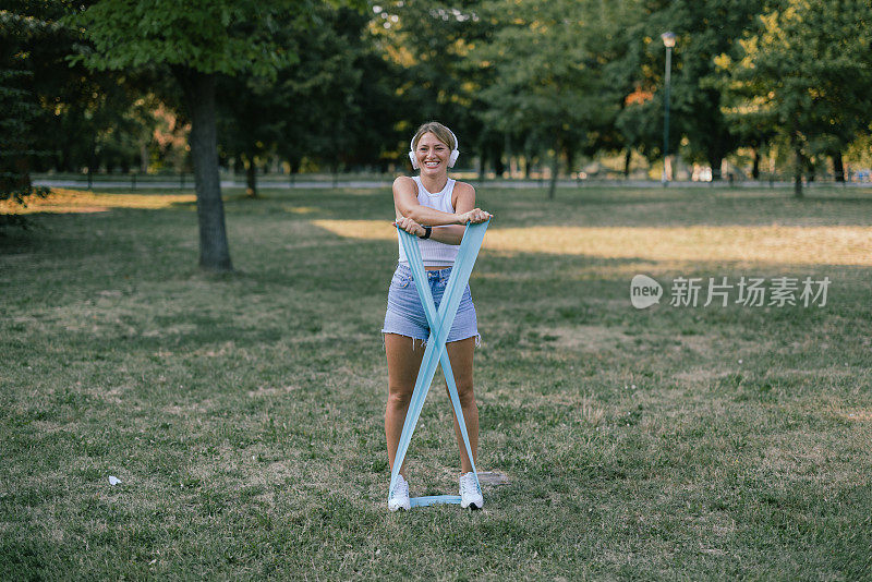 一位年轻的女运动员正在公园里做早操。