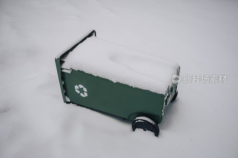 埋在雪地里的绿色回收箱