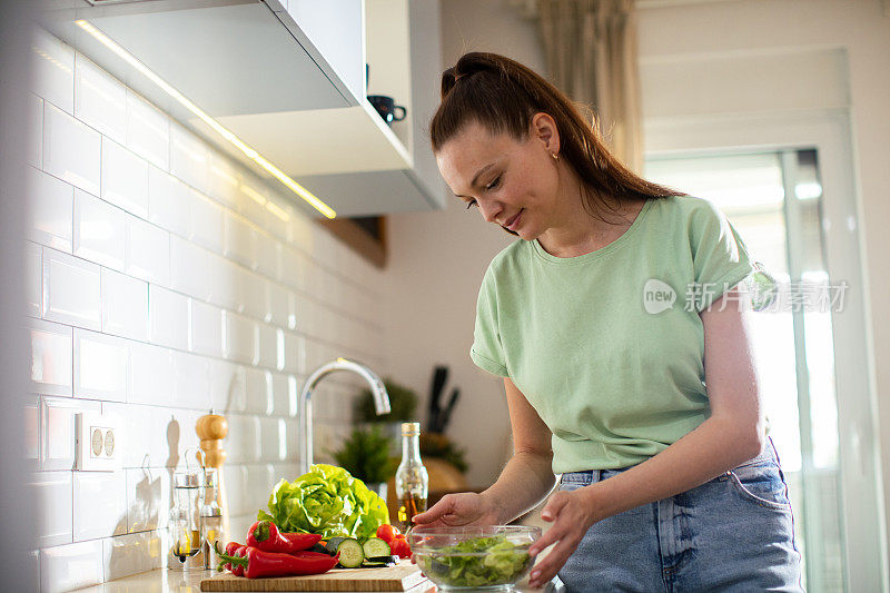 年轻女子在家里的厨房里切菜和准备蔬菜