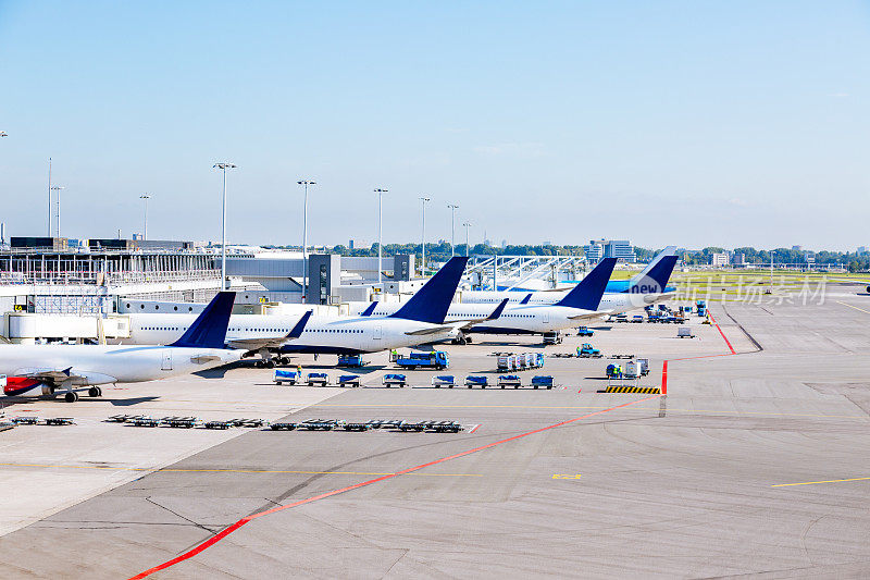停在机场停机坪门口的飞机，背景是一座航站楼。