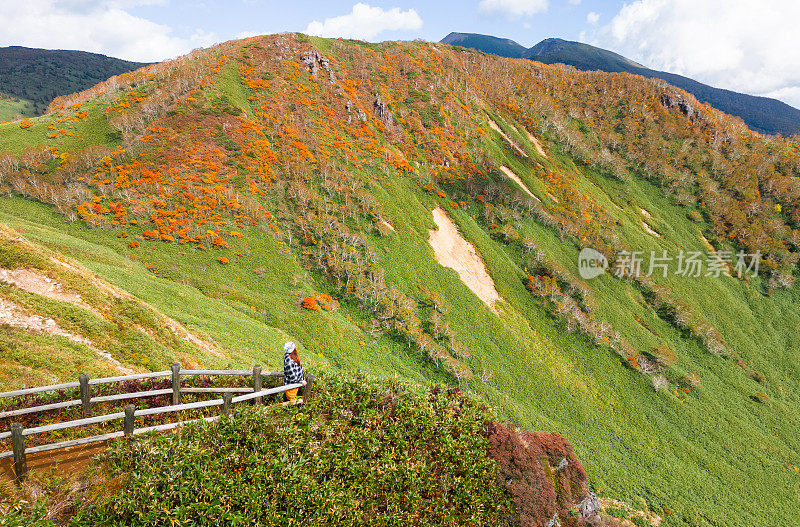 一位女性徒步旅行者停下来欣赏秋天的山景