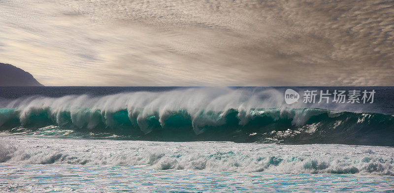 下午晚些时候，夏威夷瓦胡岛日落海滩上的管状波浪正在形成。