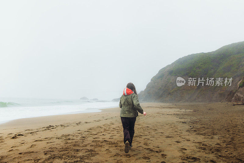 一个快乐的女人在加利福尼亚旧金山的海滩上散步