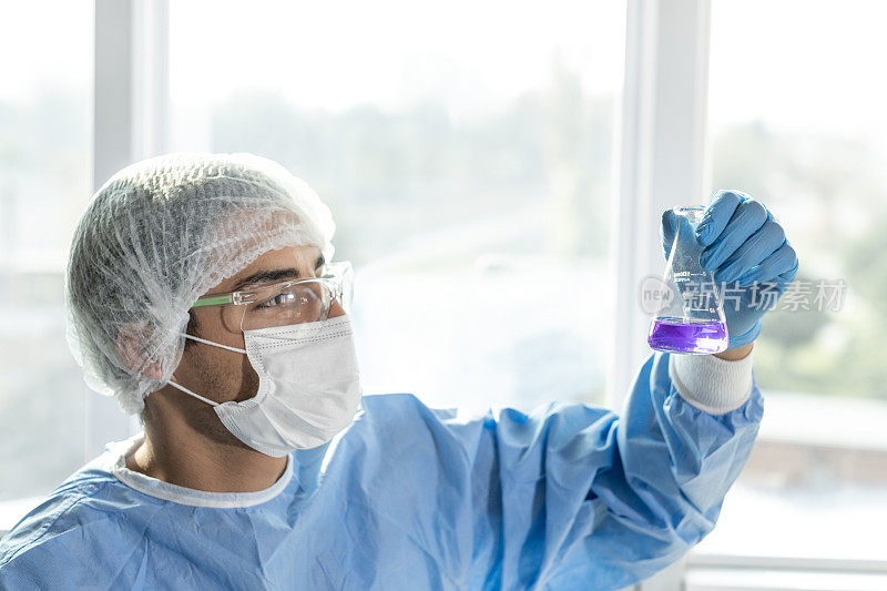 戴防护口罩和实验室手套调查样品的科学家或实验室研究人员。医学诊断、研究和科学背景。