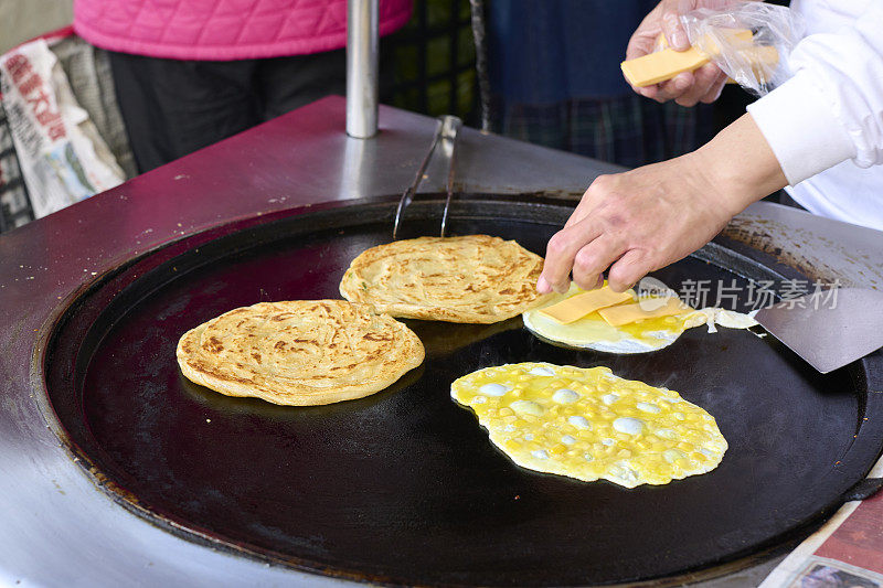 俯瞰美味的中国煎蛋卷或葱饼与奶酪和鸡蛋。中国煎蛋卷是一种用打散的鸡蛋用油煎制而成的手工煎饼。它通常与奶酪、玉米粒、火腿等馅料折叠在一起。