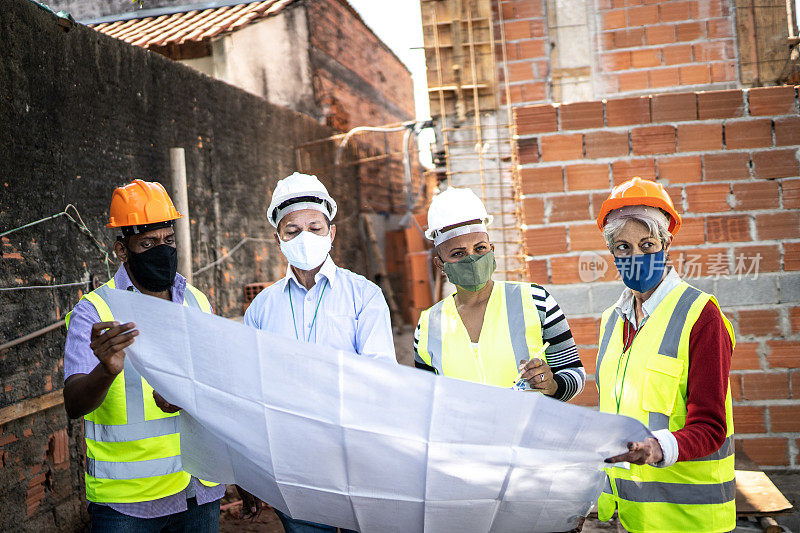 建筑工人戴着防护口罩讨论建筑方案