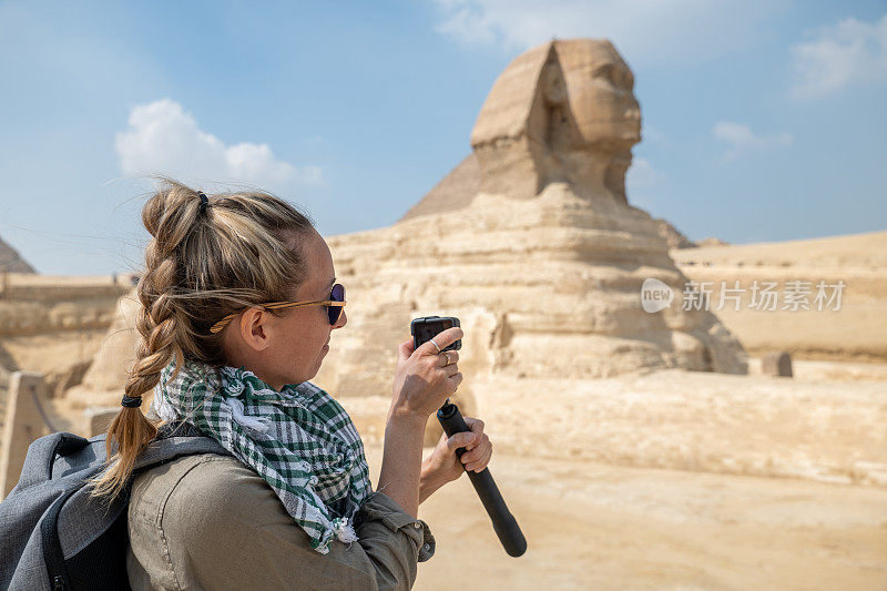 一名女游客在埃及拍摄狮身人面像，她用的是动作相机