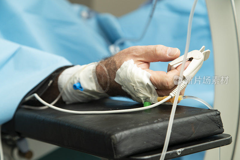 病人躺在手术台上，手上拿着脉搏血氧计。