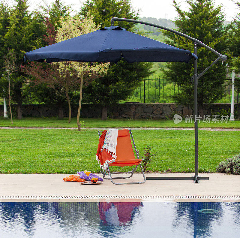 花园游泳池旁有阳伞、躺椅、靠垫和饮料