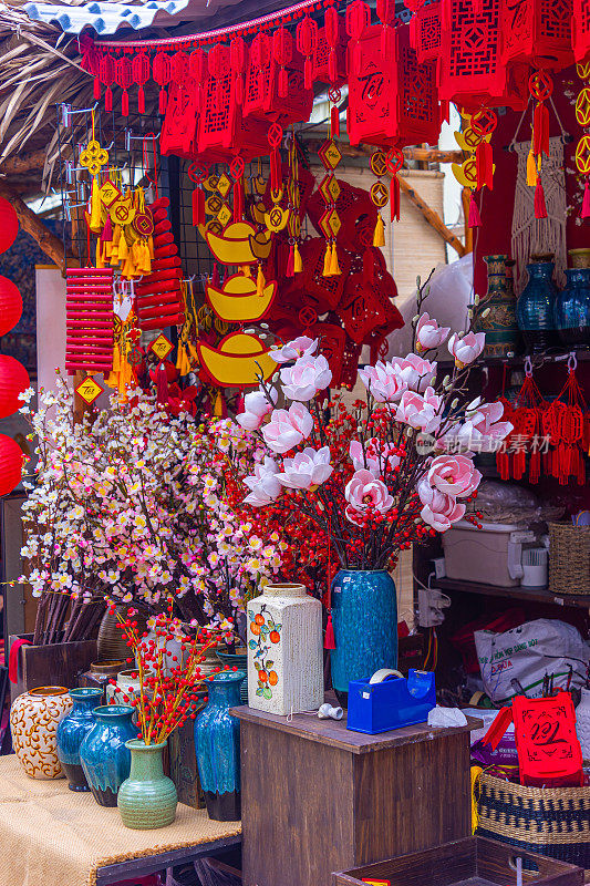 越南春节传统装饰。装饰塑料黄杏花，红色和镀金的装饰品在新年市场。