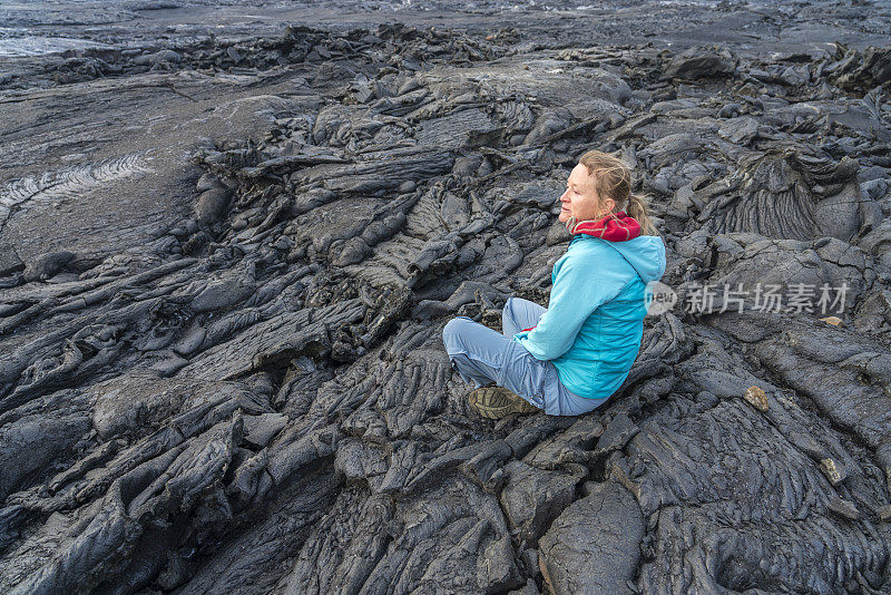 女人们坐在Fagradalsfjall火山冷却的黑色熔岩上